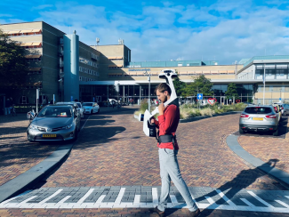 Image of walking person wearing a mobile scanner in front of the hospital